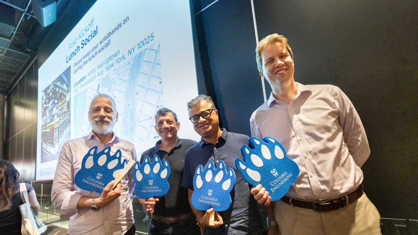 Vishal Misra and three Columbia professors pose with blue Columbia Engineering paw signs during orientation