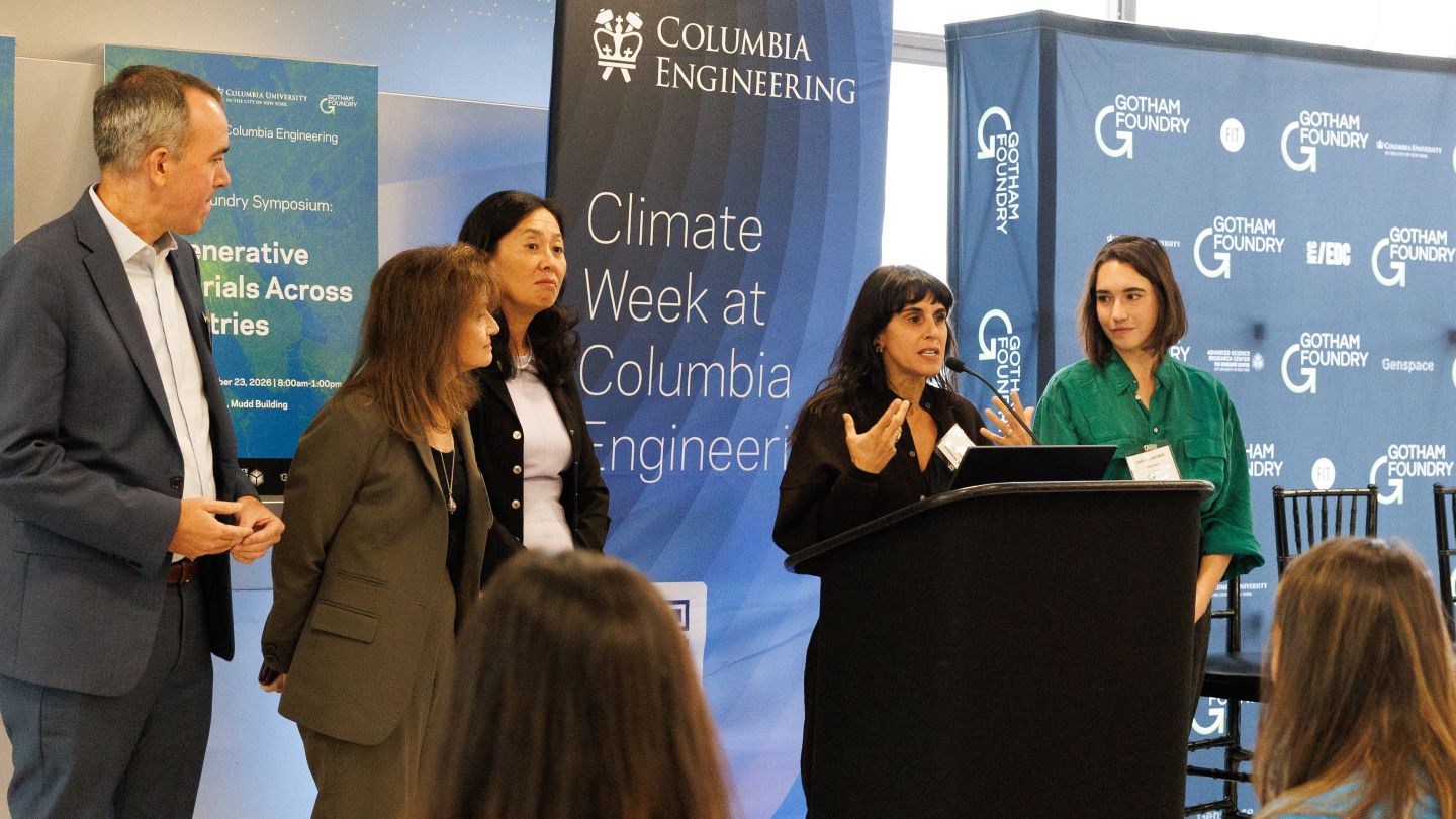 Gotham Foundry Co-Director Theanne Schiros speaking from a podium alongside other symposium participants at the Gotham Foundry symposium.