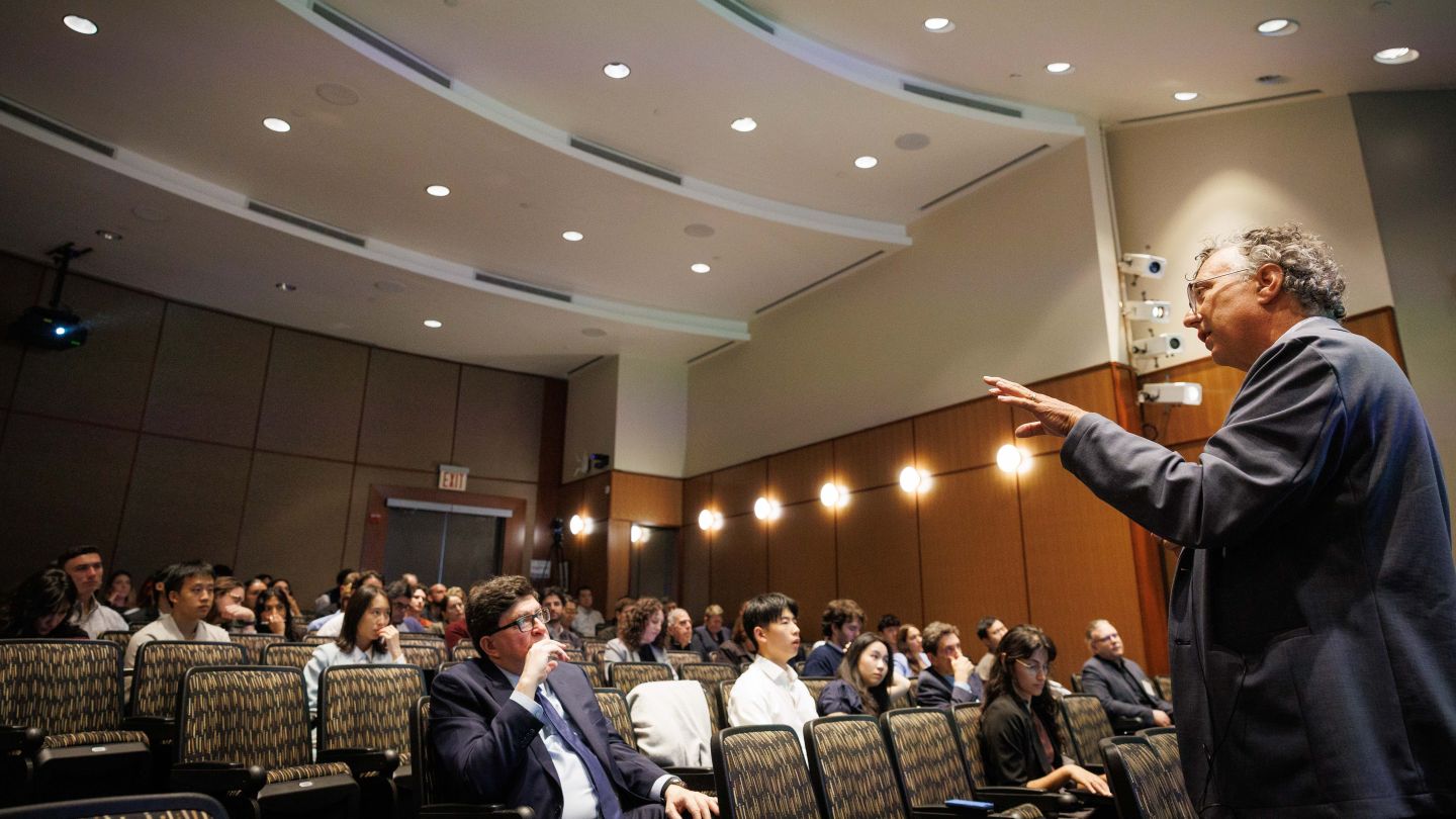Alan West speaking and gesturing to an audience in an auditorium at Columbia Engineering.