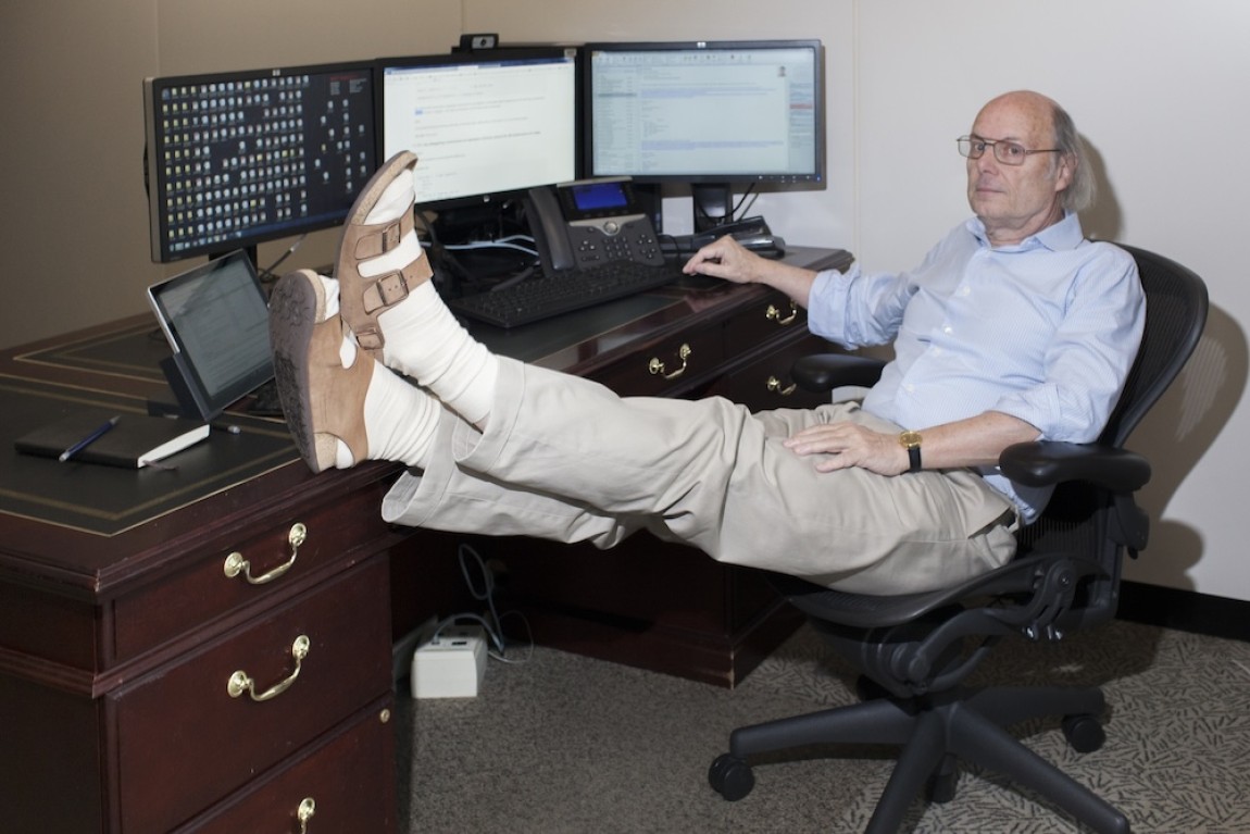 Bjarne Stroustrup at his desk with 3 monitors, his feet propped up on the desk
