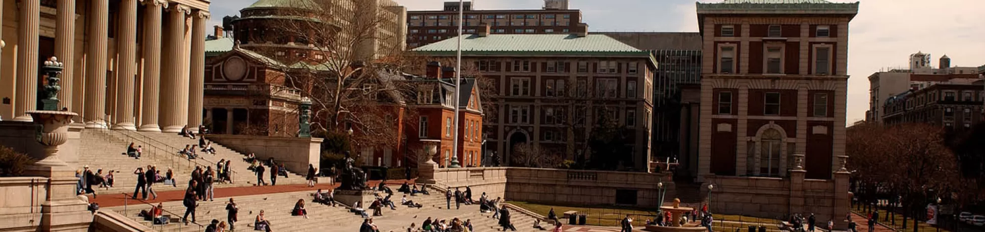 A wide shot of Columbia University campus with students bustling around in a plaza.
