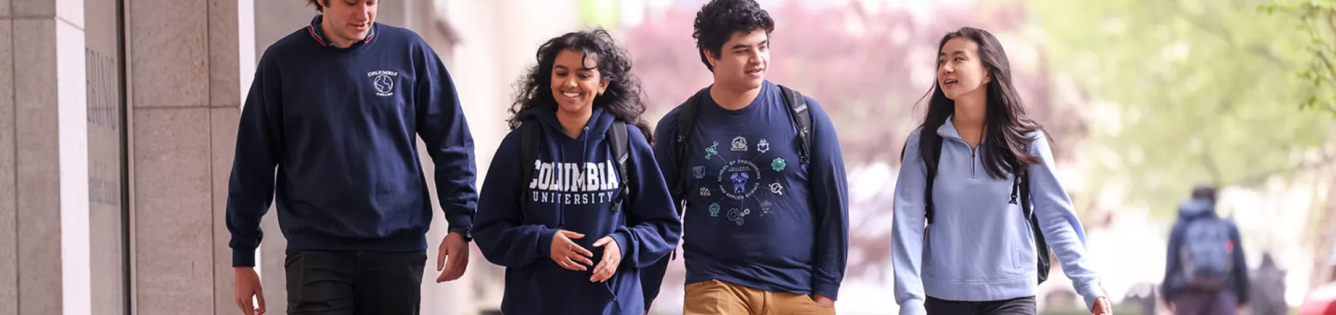 Four Columbia University undergraduate students walking together down a New York City sidewalk.