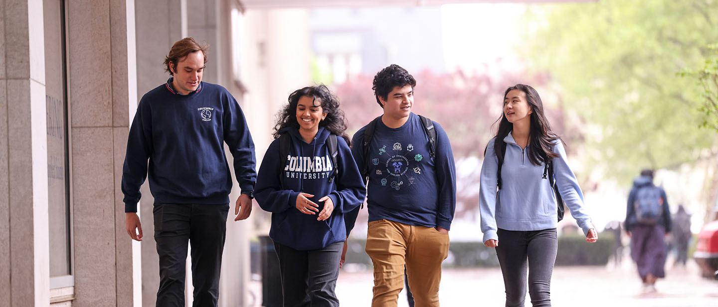 Four Columbia University undergraduate students walking together down a New York City sidewalk.