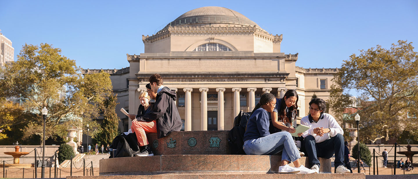 A group of students sit on the steps of Columbia University's campus.