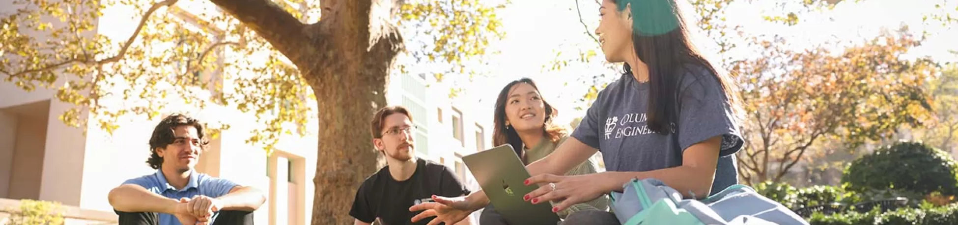 Columbia Engineering students sitting together outdoors on the grass.