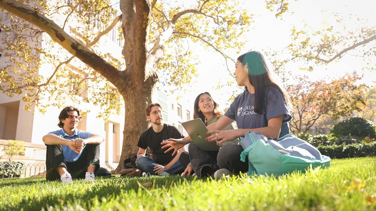 Columbia Engineering students sitting together outdoors on the grass.