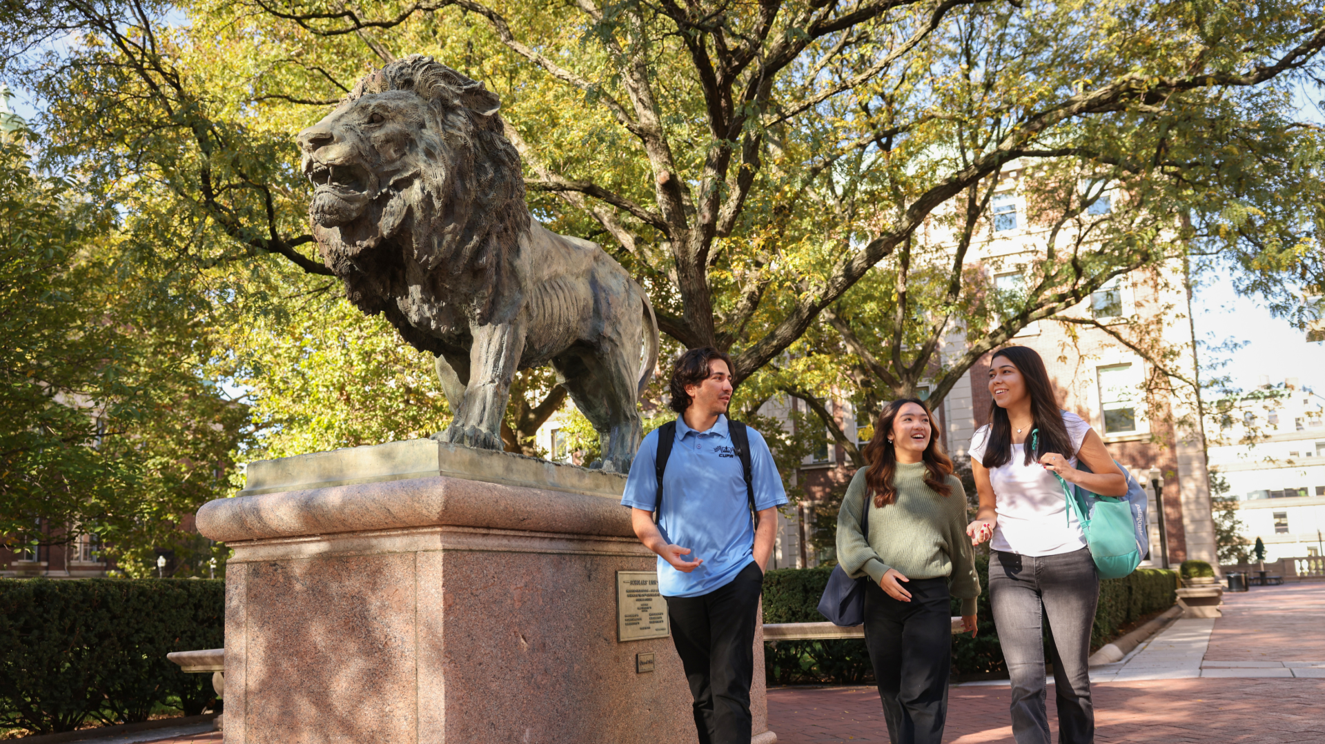 Three Columbia Engineering students talk near the Scholar Lion sculpture.