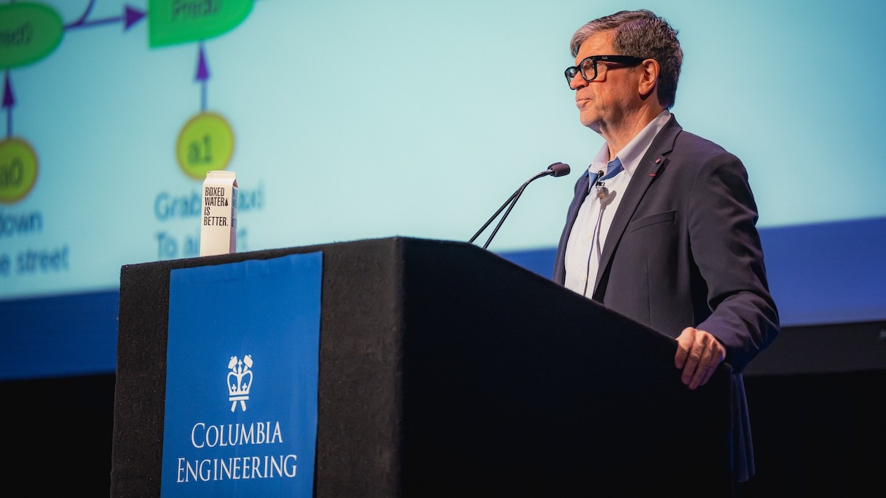 Yann Lecun standing behind a podium with a microphone. The podium's banner reads "Columbia Engineering"