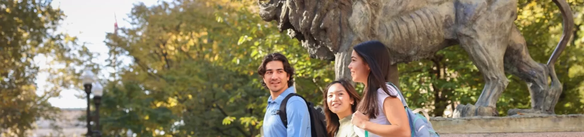 Three Columbia students walking by the Scholar's Lion