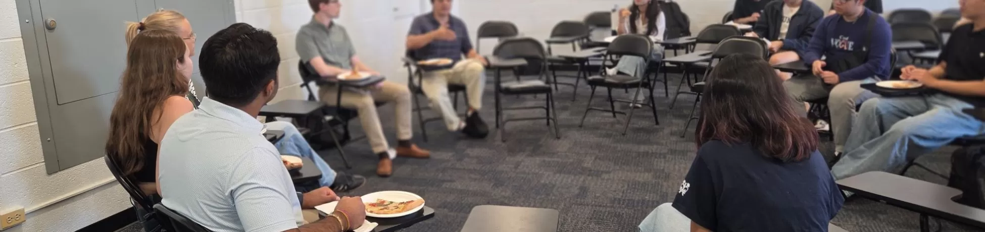 people sitting in a classroom, where desks are arranged in a circle