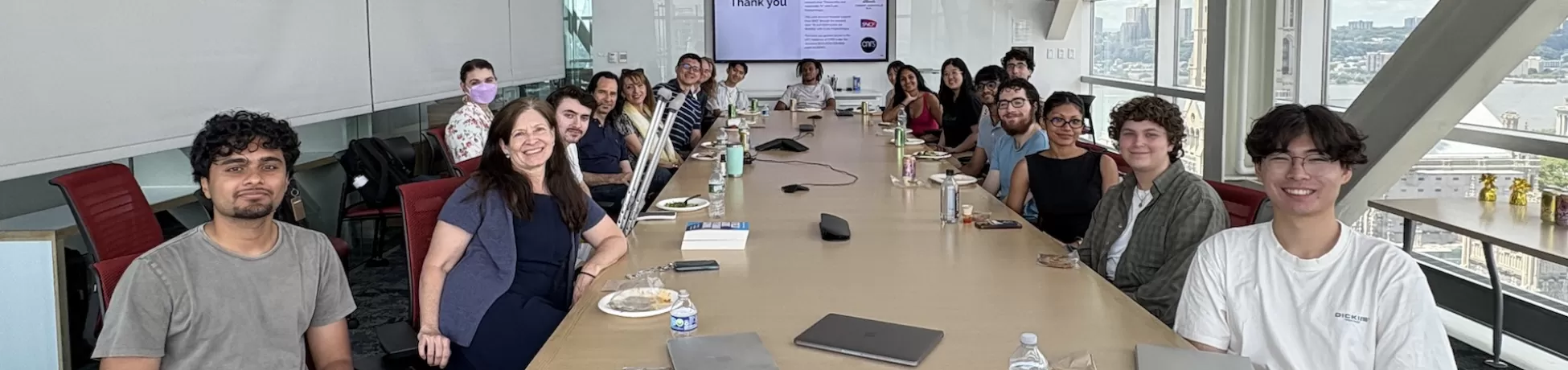 image of cyber nyc participants gathered at a large conference style table with ending slides of a powerpoint at the back