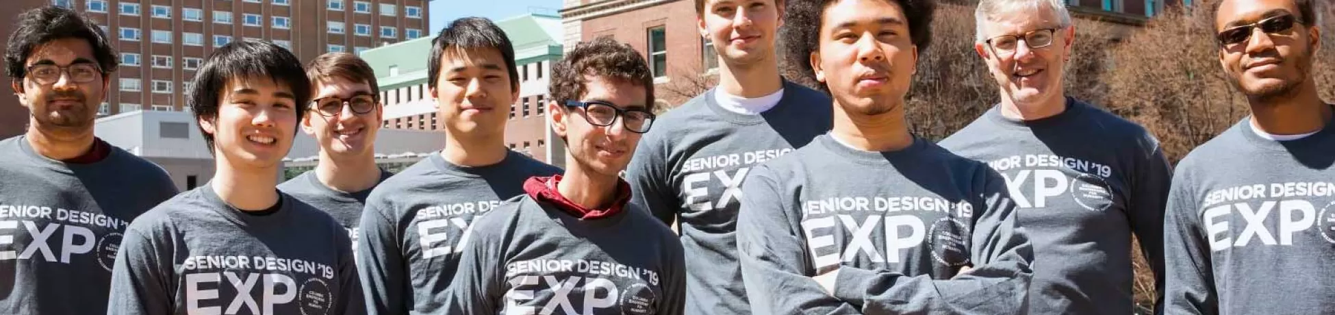 students and a professor standing outside wearing 2019 Senior Design Expo shirts