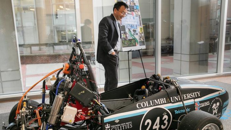 A person standing next an electric formula racing car.