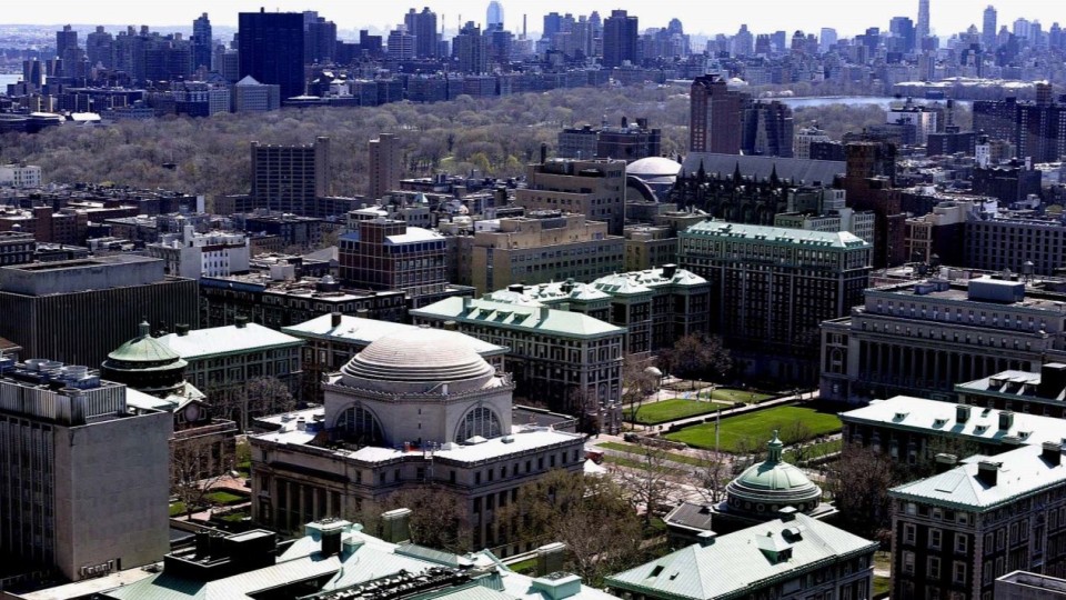 A high-up view of Columbia University and Barnard College in front of downtown Manhattan