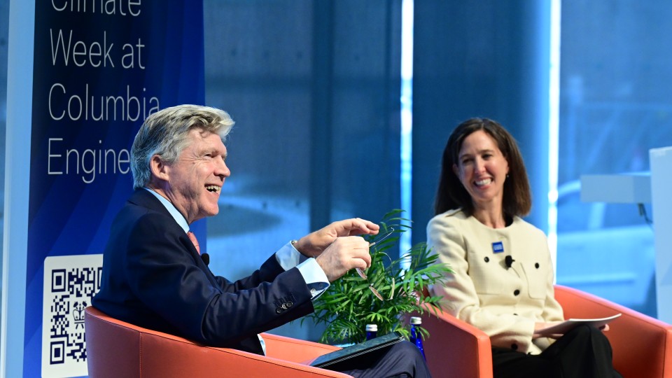  image of two speakers talking, with a climate week banner behind them
