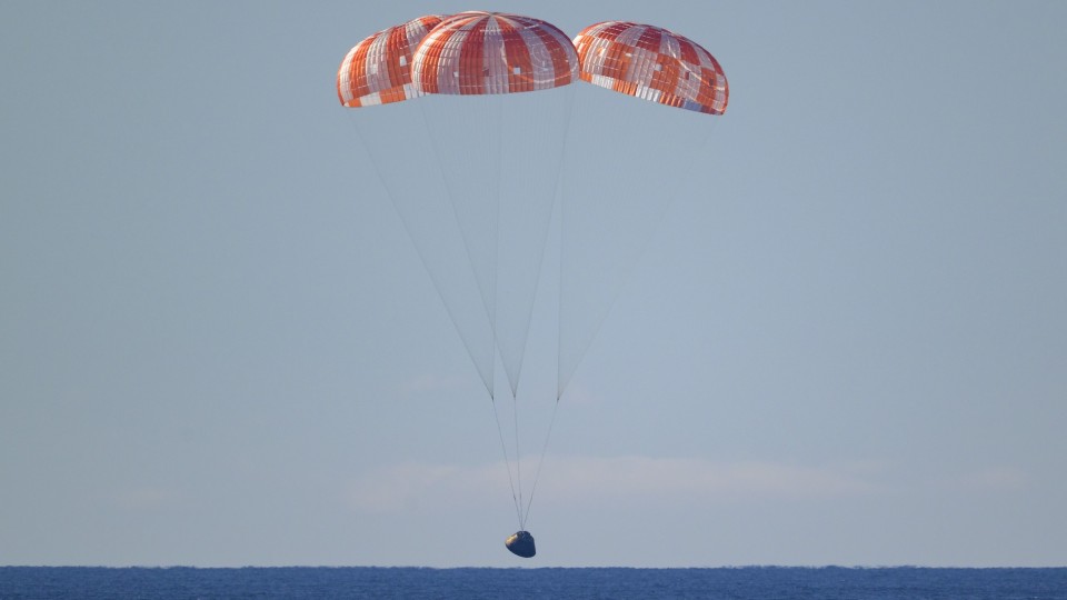 NASA’s Orion spacecraft with Artemis II crewmembers seen under parachutes as it lands in the Pacific Ocean off the coast of California, Friday, April 10, 2026. 