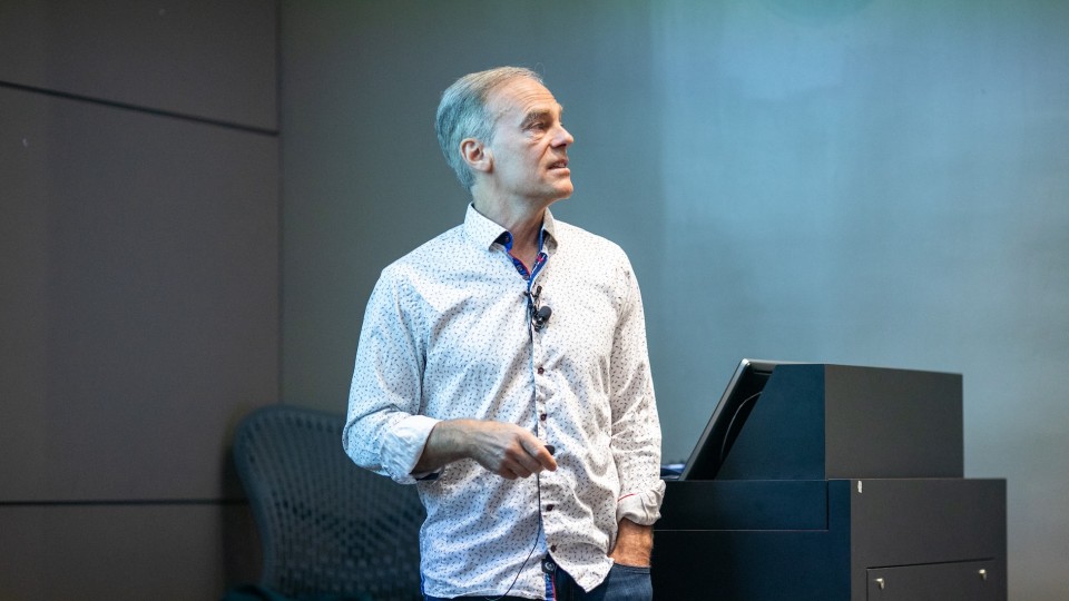Richard Zemel standing at front of an auditorium, looking toward an audience.