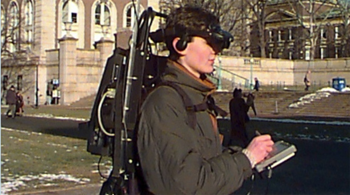 A person with a large computer strapped to their back, wearing a headset