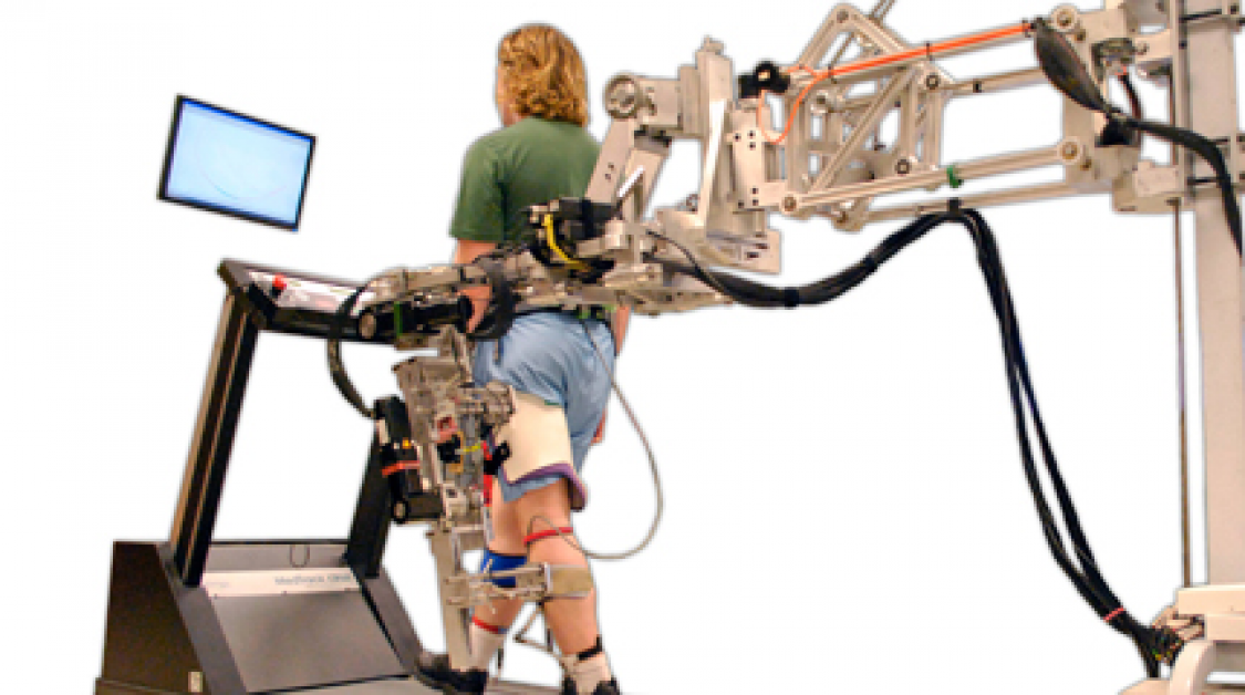 A man walking on a treadmill assisted by a robot