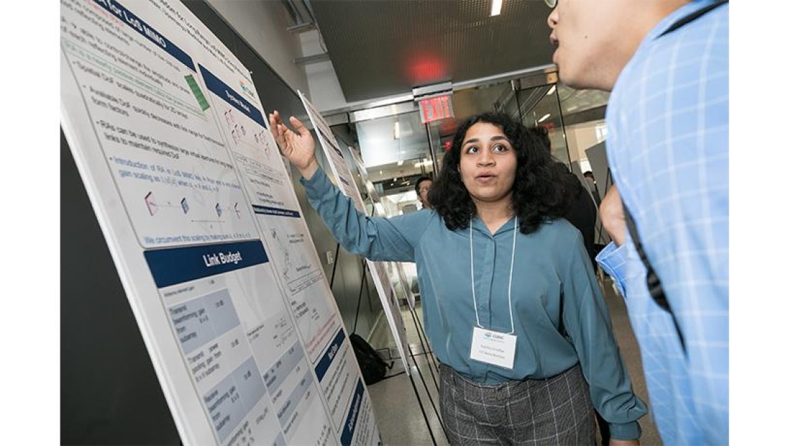 A person gestures toward a poster.