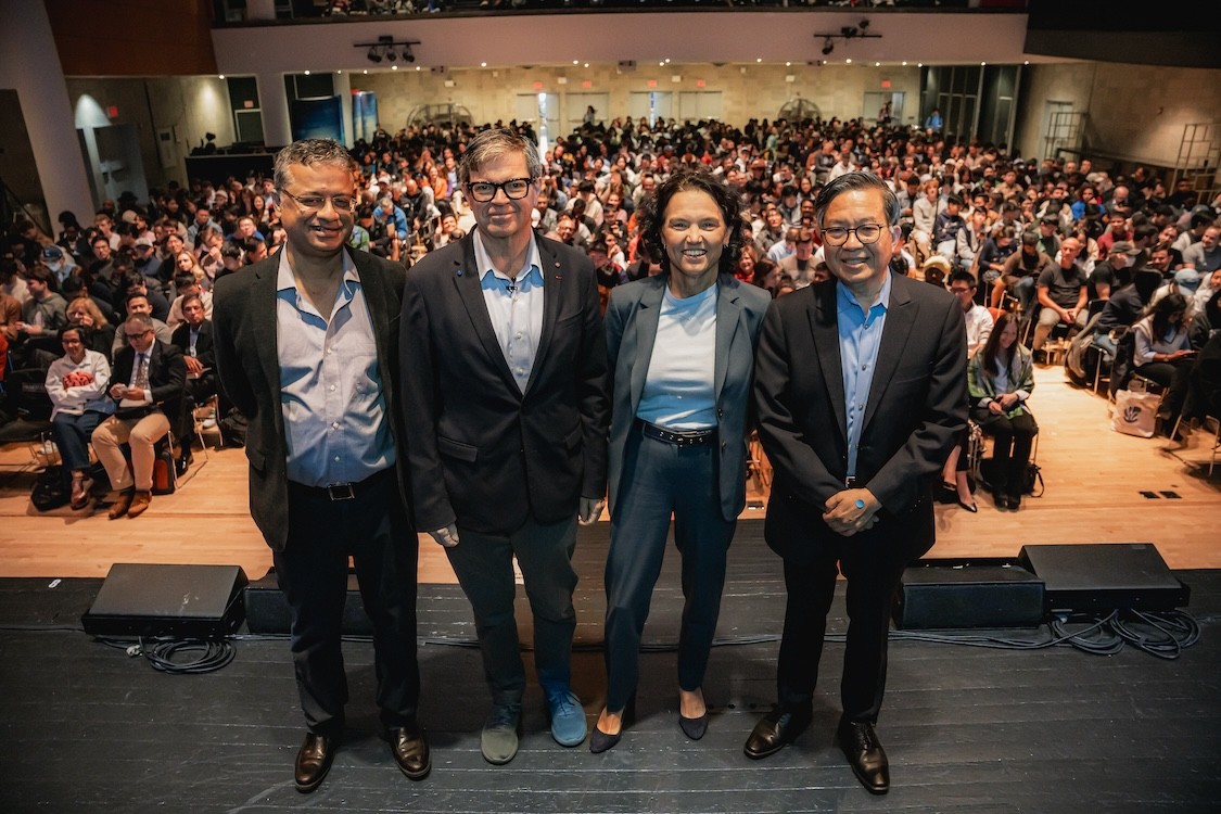 Standing in front of a crowded auditorium and posing for a photo from left to right, Columbia Engineering Vice Dean of Computing and AI Vishal Misra; Meta Chief AI Scientist Yann LeCun; Columbia University Interim President Katrina Armstrong; and Columbia Engineering Dean Shih-Fu Chang