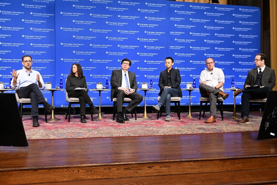Six panel members sitting on stage.