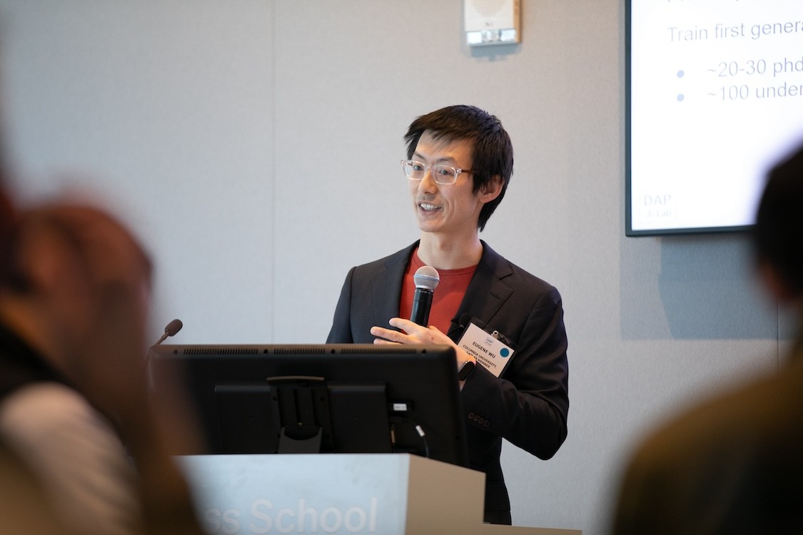 Eugene Wu standing at a podium and holding a microphone