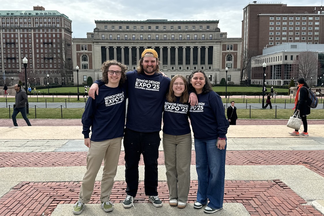Four people smiling for a photo in front of Butler Library. Their shirts read "Senior Design Expo '25 Columbia Engineering"