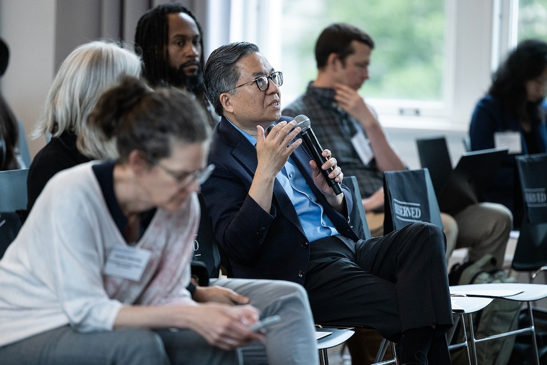 Shih-Fu Chang sitting in a crowd and holding a microphone