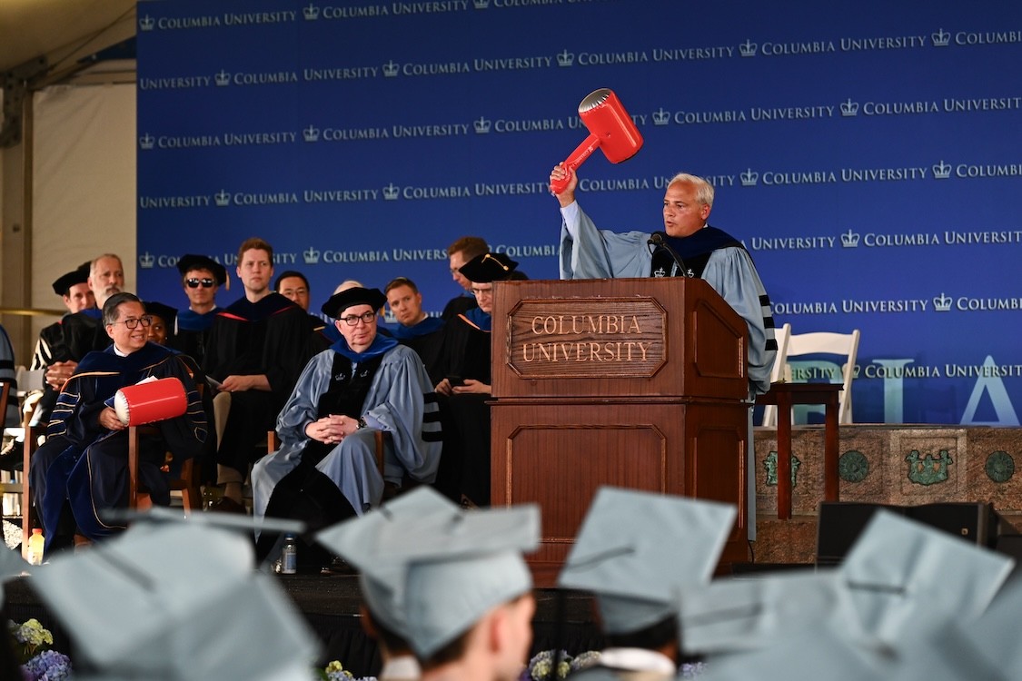 Thomas Caulfield at a podium raises a large red ceremonial mallet while Columbia Engineering faculty look on during 2026 Columbia Engineering Class Day ceremonies.