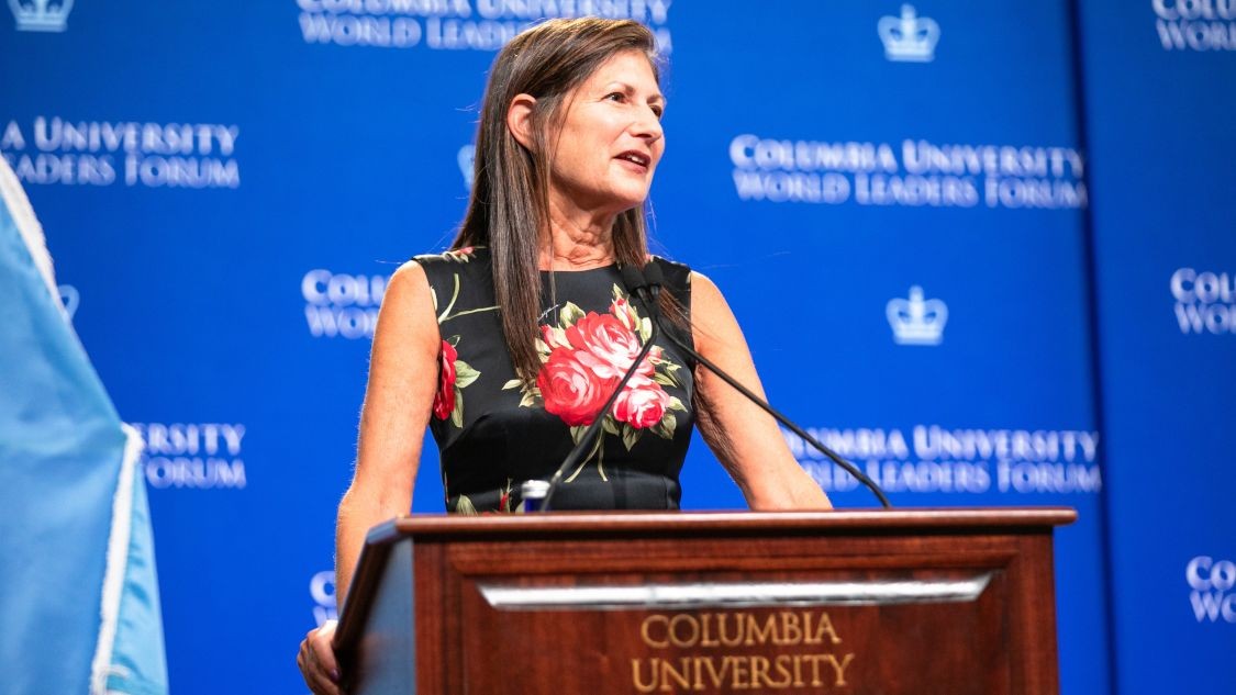 Sarah Cole speaking behind a Columbia University-branded podium at the Columbia University World Leaders Forum.