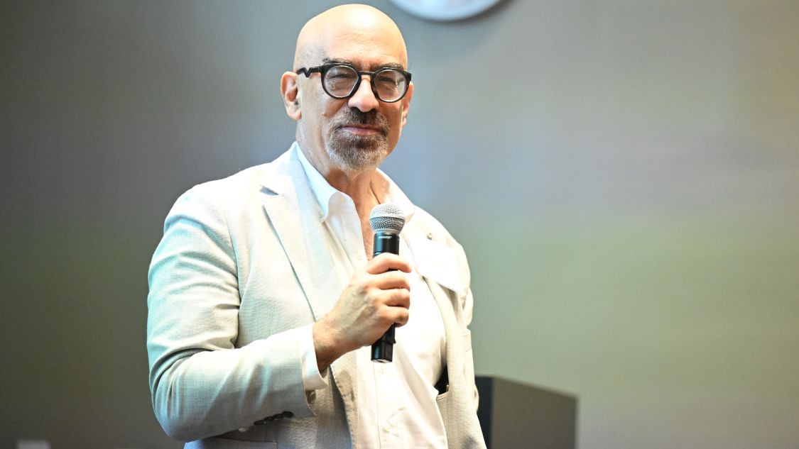 David Spergel speaks while holding a microphone.