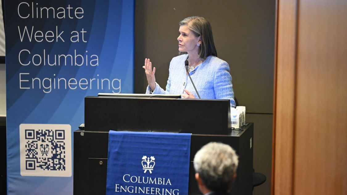 Angela Olinto speaks behind a podium next to a Climate Week at Columbia Engineering sign.