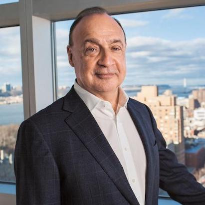 Len Blavatnik standing by a window with views of New York City in the background
