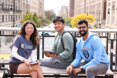 Three Columbia Engineering students pose for a photo on a bridge overlooking a busy NYC street.