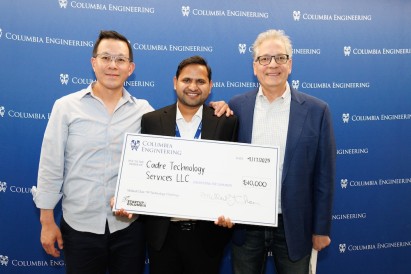 photo of 3 people, with a large check