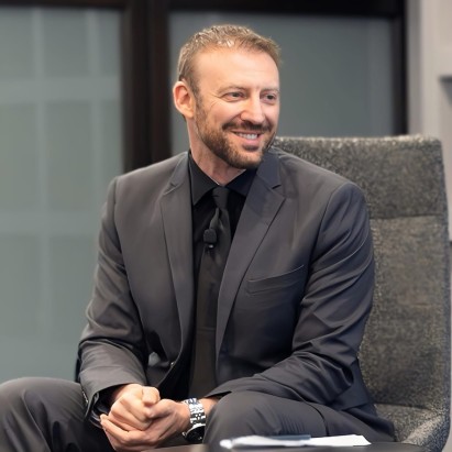 Phil Shpilberg seated on an armchair, facing right