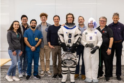 group photo, with person in the middle wearing astronaut gear