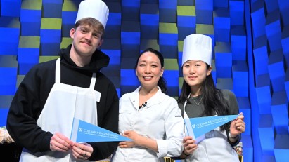 2 students posing with Judy Joo (center), holding Columbia Engineering pennant