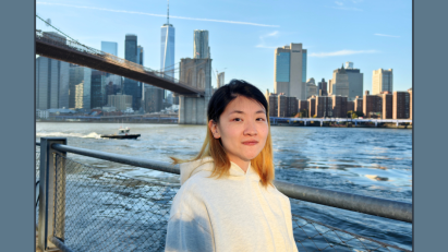 Xuanjing Chu posing for a photo near the East River with the Brooklyn Bridge and Manhattan Skyline in the background